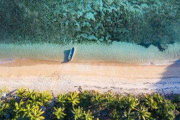 Drone view of a boat, beach, and coral reef in Fiji