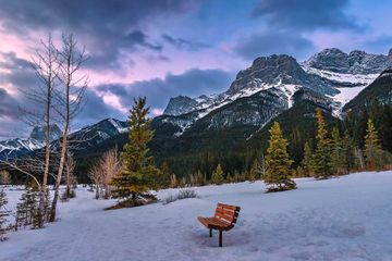 A bench in a winter park in the Canmore mountains.