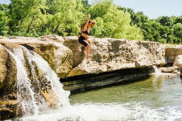 A couple jumps into a swimming hole in Austin, Texas.