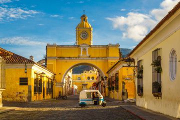 A tuk-tuk taxi passes in from of The Arch of Santa Catalina in Antigua, Guatemala.
