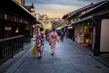 Two women in traditional dress walking through a preserved area of Kyoto