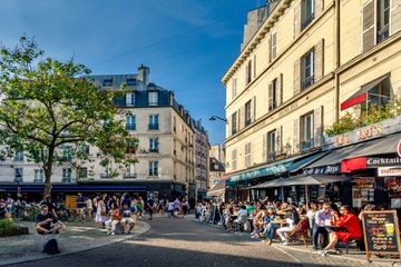People dining at restaurants on the street in Paris, France on a sunny day