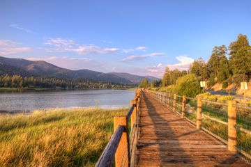 the wooden log boardwalks of Stanfield Marsh stretching along side the beautiful lake of Big Bear. Gorgeous blue sky and mountain forest.