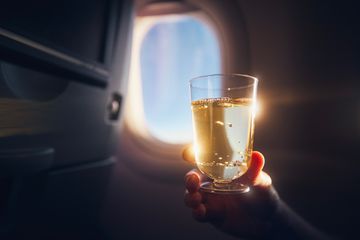 A man holding a glass of champagne on board an airplane