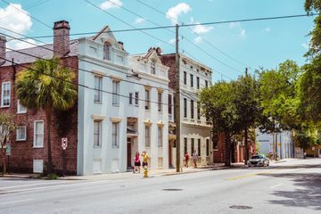 People walk by old buildings in Charleston