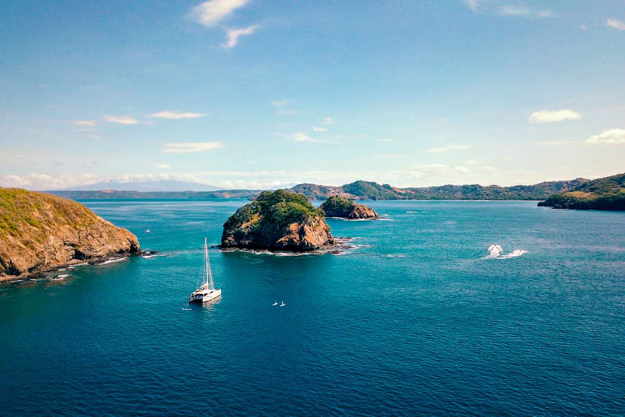 A catamaran and paddleboarders of the coast of Costa Rica
