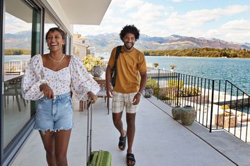 Young couple walking on vacation house deck by sea in summer 