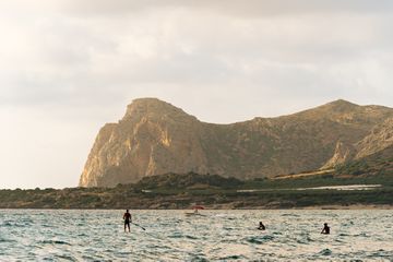 People on surf boards and paddle boards in the ocean at Crete