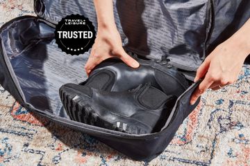 Hands putting a pair of shoes in a Lo & Sons Catalina weekender bag