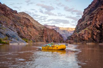 Man rows raft down the Colorado River in the Grand Canyon