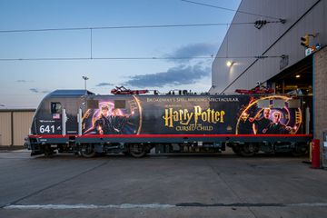 An Amtrak train with a Harry Potter and the Cursed Child wrap at a train facility 