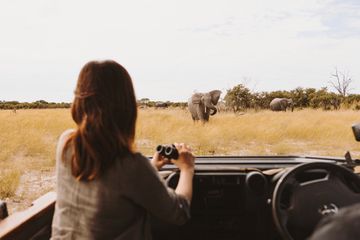 A woman watching elephants seen on a game drive with the Wilderness Vumbura Plains camp in Botswana 