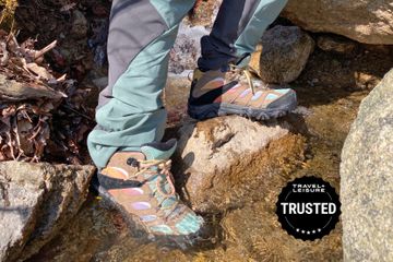 Person standing on a rock in a river wearing Merrell Moab 2 Mid GTX hiking boots