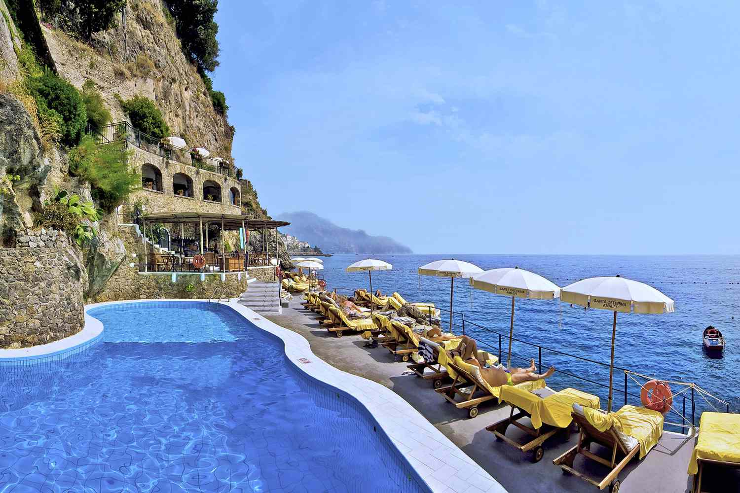 Swimming pool and lounge seating with view of water at Hotel Santa Caterina