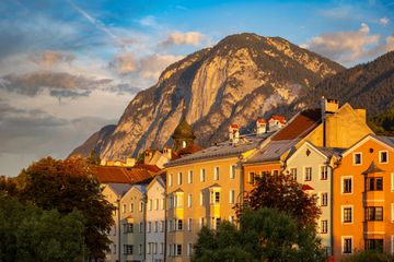Houses along the river at sunrise with towering mountain behind in golden light