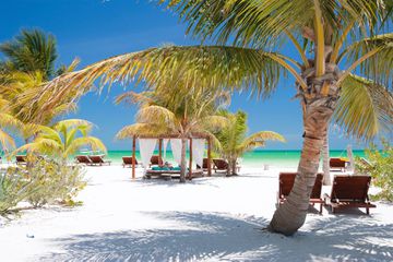 Beach beds among palm trees at perfect tropical coast on Holbox island in Mexico
