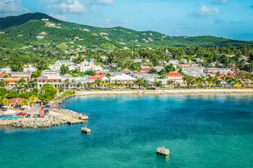 Beautiful scenery with harbor of St Croix, green mountain, water and town along the coastline.