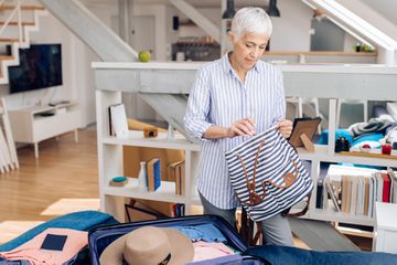 Mature woman packing her suitcase for vacation
