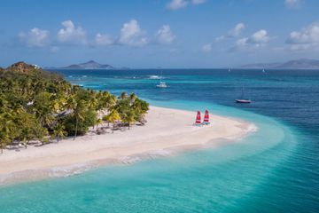 View of Palm Island Resort and Spa in The Grenadines with sailboats in view along the crystal blue waters