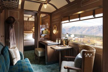 Interior luxury suite on Scotland's Belmond train with a bed, dining table and couch and scenic views