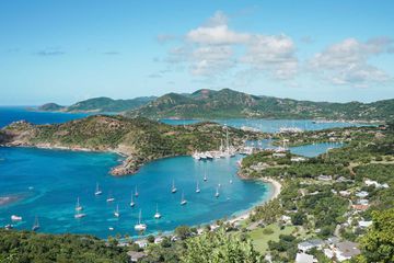 Aerial view of Shirley Lookout on St John, Antigua. Lush green landscape of the island with bright blue waters and boats scattered along the bay.