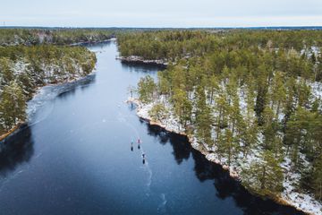 Aerial view of three people skating on a frozen lake in Sweden