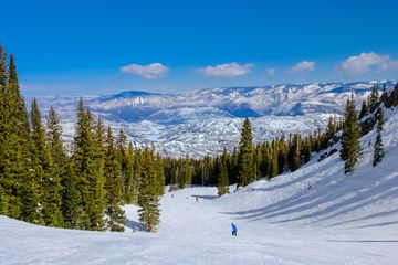People skiing in Colorado ski resort in Snowmass on clear winter day