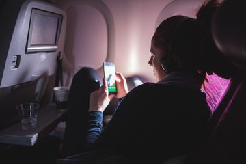 Woman Using Cell Phone And Sitting Comfortably in Airplane