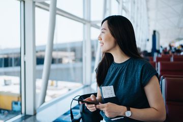 A young woman holding flight ticket and passport waiting for her flight 